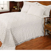 A white bed adorned with a white comforter and quilt, emphasizing a clean and tranquil bedroom environment.